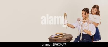 Banner der charmanten Frau und ihrer Tochter, die sich mit Juwelen vor hellem Hintergrund anprobiert haben. Werberaum Stockfoto