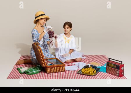 Urlaubstag einer jungen, fröhlichen Familie, Mutter und Tochter mit Picknick vor hellem Hintergrund Stockfoto