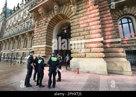 Hamburg, Deutschland. 30. März 2023. Polizeibeamte stehen vor dem Eingang zum Rathaus, das mit Farbe bedeckt ist. Einen Tag vor dem Hamburger Besuch des britischen Königs Karl III. Und seiner Frau Camilla haben Klimaaktivisten der Last Generation das Rathaus mit orangefarbener Farbe besprüht. Kredit: Bodo Marks/dpa/Alamy Live News Stockfoto