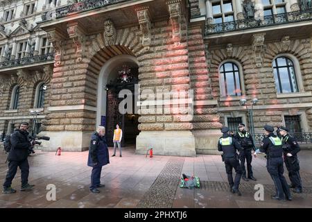 Hamburg, Deutschland. 30. März 2023. Polizeibeamte stehen vor dem Eingang zum Rathaus, das mit Farbe bedeckt ist. Einen Tag vor dem Hamburger Besuch des britischen Königs Karl III. Und seiner Frau Camilla haben Klimaaktivisten der Last Generation das Rathaus mit orangefarbener Farbe besprüht. Kredit: Bodo Marks/dpa/Alamy Live News Stockfoto