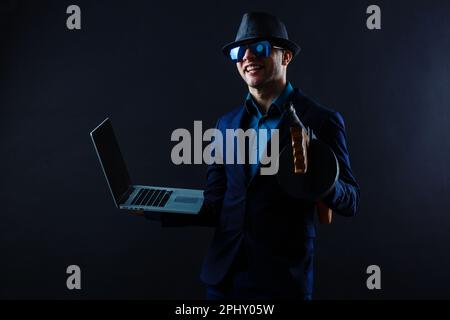 Geschäftsmann in Sonnenbrille mit Maschinengewehr und Laptop Stockfoto