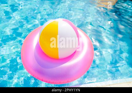 Aufblasbarer Poolball auf Rettungsring im Pool Stockfoto