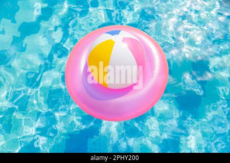 Aufblasbarer Poolball auf Rettungsring im Pool Stockfoto