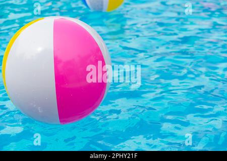 Rosafarbener Gummiring mit aufblasbaren Bällen und einem Ball im Pool Stockfoto