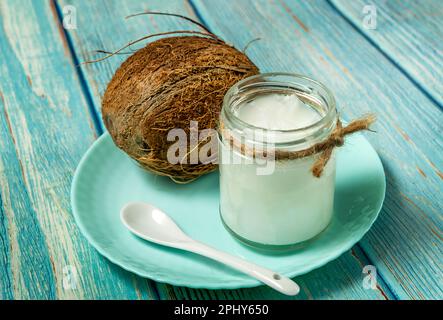 Kokosöl und frische Kokosnüsse auf altem Holztisch Stockfoto