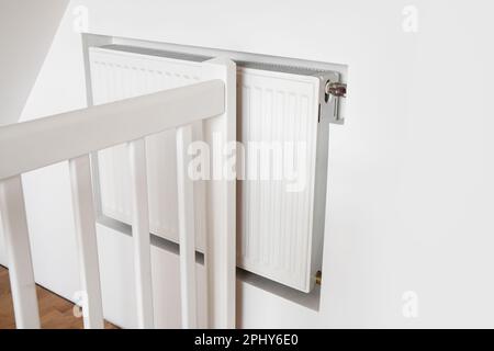 Weißer Warmwasserbereiter in Trockenbauwänden in Innenräumen. Speziell angefertigte Struktur, die jedoch die Heizleistung verringert. Stockfoto