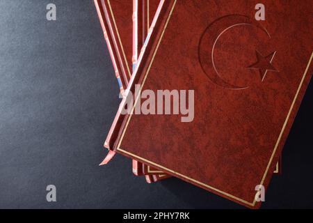 Bücherstapel mit braunem Ledereinband und eingraviertem Symbol islamischer Kultur und Religion auf dem schwarzen Tisch. Draufsicht. Stockfoto