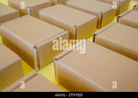 Viele Kraftkarton-Boxen auf gelbem Hintergrund. Ich packe das Paket Stockfoto