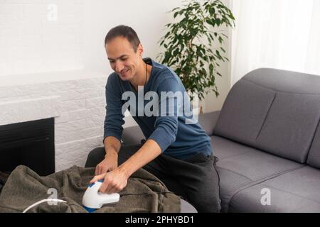 Der Mann entfernt Stofftabletten mit Flusensieb. Stockfoto
