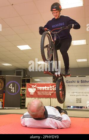 Hamburg, Deutschland. 30. März 2023. Thomas Klausner springt im Platteninstitut für Deutschland 60-mal in einer Minute über einen Menschen in Bauchlage auf seinem Fahrrad und setzt damit einen Weltrekord. Kredit: Ulrich Perrey/dpa/Alamy Live News Stockfoto