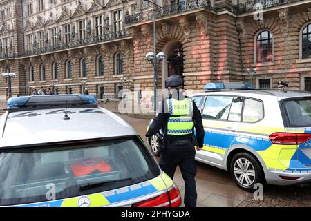 Hamburg, Deutschland. 30. März 2023. Polizeibeamte stehen vor dem Eingang zum Rathaus, das mit Farbe bedeckt ist. Einen Tag vor dem Hamburger Besuch des britischen Königs Karl III. Und seiner Frau Camilla haben Klimaaktivisten der Last Generation das Rathaus mit orangefarbener Farbe besprüht. Kredit: Bodo Marks/dpa/Alamy Live News Stockfoto