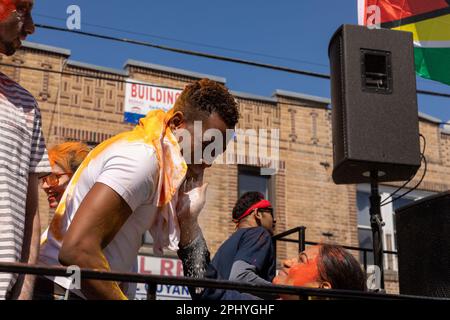 Eine Gruppe von Menschen, die bei der Phagwah Holi Parade 2023 in Queens, NY, Farbpulver auf sich verteilen Stockfoto