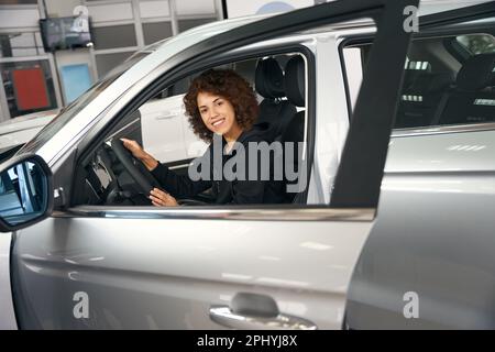 Glückliche Multirassenkäufer sitzen im Salon eines brandneuen Autos Stockfoto