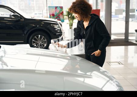 Lächelnder Autohändler, der ein neues Fahrzeug auswählt Stockfoto