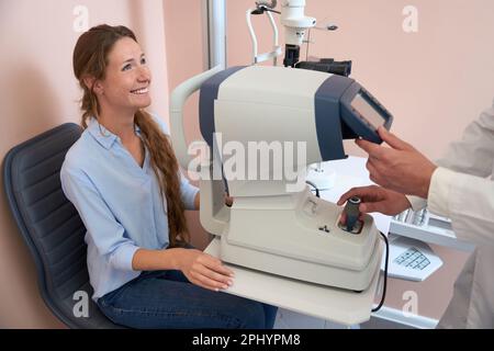 Hübsche Frau sitzt vor der Spaltlampe in der modernen Klinik Stockfoto