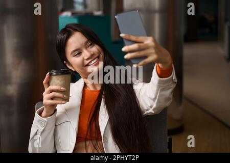Fröhliche Büroangestellte, die in der Kaffeepause Selfie macht Stockfoto