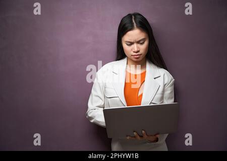Konzentrierte junge Frau, die drinnen an einem Laptop arbeitet Stockfoto