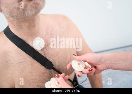 Zugeschnittenes Foto einer Krankenschwester, die holter auf die Brust des Patienten im Krankenhaus klebt Stockfoto