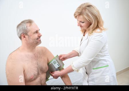 Arzt, der den holter-Monitor an der Hand anlegt Stockfoto