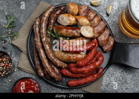 Set aus verschiedenen leckeren Snacks und Bier auf dunkelgrauem Tisch, flach liegend Stockfoto