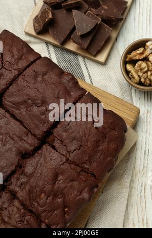 Köstliche frisch gebackene Brownies, Walnüsse und Schokoladenstücke auf einem weißen Holztisch, flach liegend Stockfoto