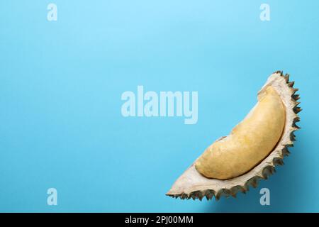 Ein Stück frische, reife Durianfrucht auf hellblauem Hintergrund, Draufsicht. Platz für Text Stockfoto