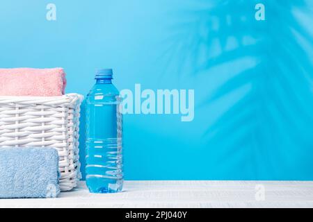 Wasserflasche und Badhandtücher auf dem Tisch mit Platz für Ihr Produkt oder Text. Spa-Arrangement Stockfoto