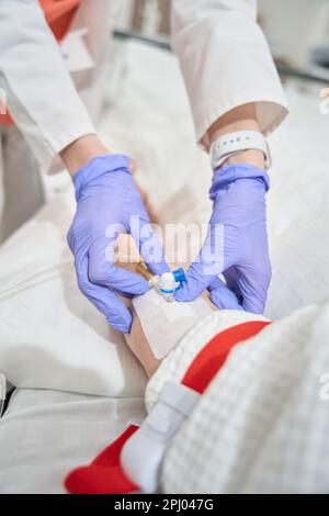 Eine nicht erkannte Krankenschwester in Handschuhen führt in der Medizinischen Klinik eine intravenöse Infusion durch Stockfoto