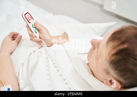 Der Patient ruft den Arzt mit einem speziellen Knopf im Krankenhaus an Stockfoto