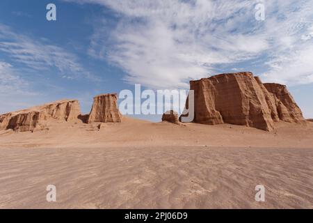 Eine atemberaubende Wüstenlandschaft mit hohen, roten Felsformationen vor einem hellblauen Himmel Stockfoto