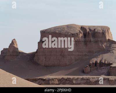 Eine atemberaubende Wüstenlandschaft mit hohen, roten Felsformationen vor einem hellblauen Himmel Stockfoto