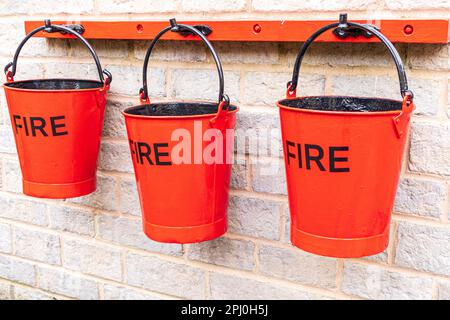 3 rote Feuereimer an der Cheltenham Spa Station an der Gloucestershire Warwickshire Railway GWSR Heritage Dampfeisenbahn, Cheltenham, Gloucestershire UK Stockfoto