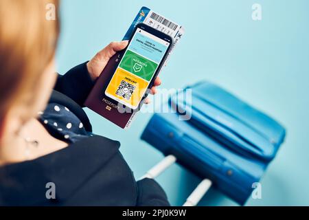 Digitales Covid-Zertifikat. Digitaler Covid-Impfpass. Passagierin mit digitalem medizinischen Pass auf Mobiltelefon, Reisepass und Flugzeug-Tic Stockfoto