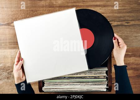 Vinyl-Schallplatten spielen. Musik von einem Vinyl-Plattenspieler hören. Retro- und Vintage-Musikstil. Frau mit analogem LP-Plattenalbum. Stapel alt Stockfoto