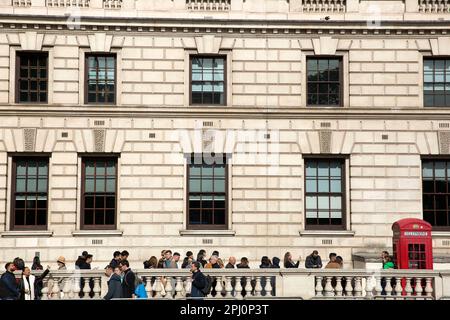 Die Leute stehen Schlange, um Fotos neben einer roten Telefonzelle in Westminster, im Zentrum von London, zu machen. Stockfoto