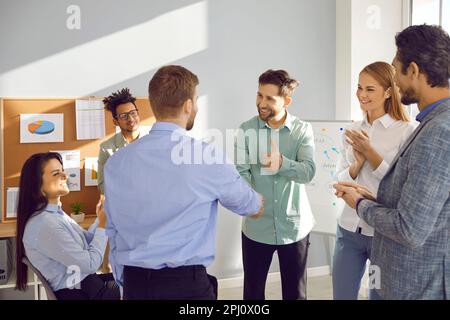 Männlicher Trainer mit Handschlag und Teammitglied im Amt Stockfoto