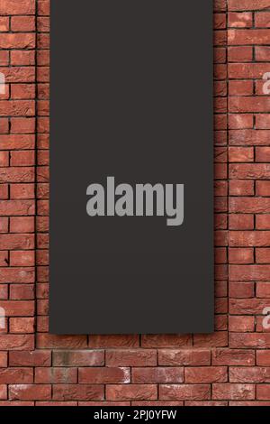 Dunkles, leeres Plakatmodell auf einer roten Ziegelwand. Stockfoto
