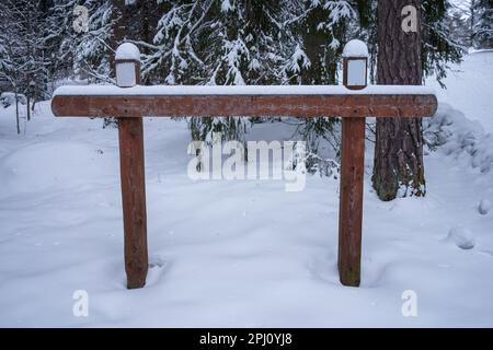Leeres Holzschild Winter. Mit Schnee bedeckt, mit Bäumen im Hintergrund Stockfoto