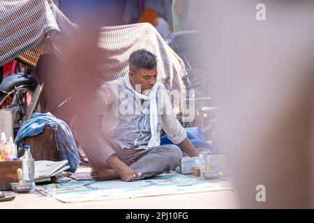 Haridwar, Indien - Okt. 2022: Straßenfriseur wartet mit Rasier- und Haarschneideausrüstung in der Nähe des ganges in haridwar auf den Kunden. Stockfoto