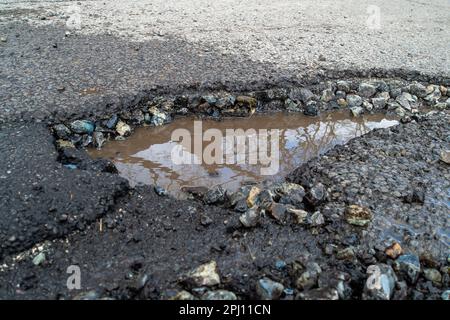 Dorney, Großbritannien. 30. März 2023. Ein weiteres tiefes Schlagloch an der Village Road in Dorney, Buckinghamshire. Leider werden viele Schlaglöcher in Dorney nur von Bauunternehmern des Buckinghamshire Council zusammengeflickt, so dass die Schlaglöcher innerhalb weniger Wochen nach Regen und kaltem Wetter zurückkehren. Autos sind heute Abend während der Hauptverkehrszeit auf den Weg von entgegenkommenden Fahrzeugen geschleudert, um diesem Schlagloch zu entgehen. Die Regierung hat in den Jahren 2023 und 2024 zusätzliche £200 Millionen Dollar für die Instandsetzung von Schlaglochen bereitgestellt. Kredit: Maureen McLean/Alamy Live News Stockfoto