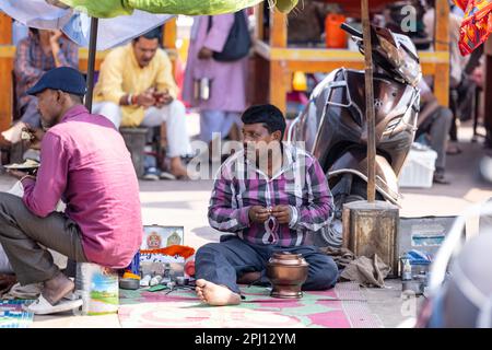 Haridwar, Indien - Okt. 2022: Straßenfriseur wartet mit Rasier- und Haarschneideausrüstung in der Nähe des ganges in haridwar auf den Kunden. Stockfoto