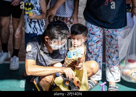 Bangkok, Thailand. 26. März 2023. Ein Vater sah, wie er gebrauchte Spielzeuge auswählte, die er seinem Sohn nacheinander auf der Wohltätigkeitsveranstaltung zeigte. Der Kinder- und Älterentag wurde vom Führer der Rong Moo-Gemeinde und der Stiftung Bangkok Community Help im Khlong Toey District, Bangkoks größtem Slum in Thailand, organisiert. (Foto: Nathalie Jamois/SOPA Images/Sipa USA) Guthaben: SIPA USA/Alamy Live News Stockfoto
