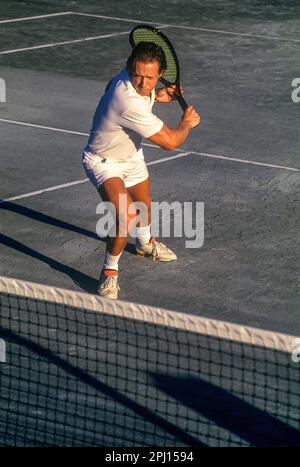 MÄNNLICHER TENNISSPIELER MIT DER RÜCKHAND AUF DEM SANDTENNISPLATZ Stockfoto
