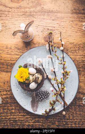 Ostertisch mit Frühlingsblumen und Besteck auf Holztisch. Osterfeiertag Im Frühling Stockfoto