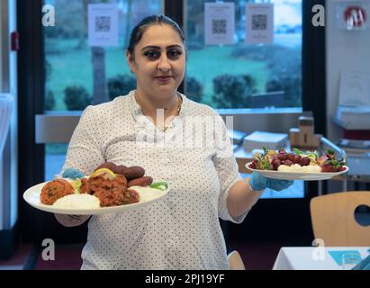 Berlin, Deutschland. 30. März 2023. Eine Frau serviert Essen im multireligiösen, schnellen Event des Hauses des Eins auf dem Campus von Wilhelmstadtschulen in Spandau. Der Fastenmonat des Ramadan ist für Muslime von besonderer Bedeutung. Tagsüber wird kein Essen gegessen und abends wird das Fastenbrechen oft gemeinsam gefeiert. Kredit: Paul Zinken/dpa/Alamy Live News Stockfoto