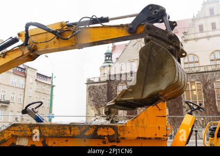 Nahaufnahme der Schaufel eines Baggers im Hintergrund von Gebäuden in der Stadt. Stockfoto