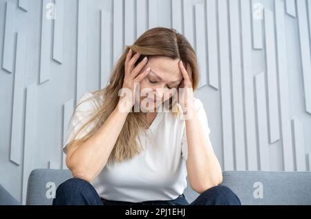 Frau mit Stressgrimmen in Schmerzen, Frau bei der Arbeit mit schmerzhaften Kopfschmerzen. Stockfoto