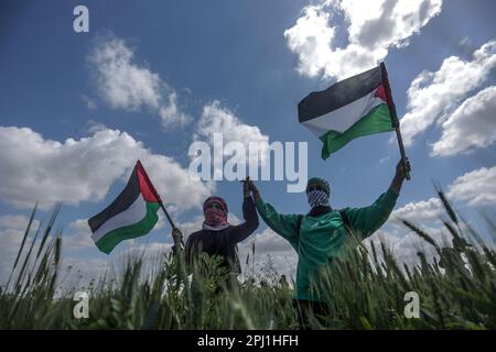 30. März 2023, Gaza-Stadt, Gaza-Streifen, Palästina: Palästinenser nehmen am 30. März 2023 an einem Protest Teil, der an der Grenze zwischen Israel und dem Gaza-Streifen im Osten des Gaza-Streifens stattfand. Der Tag erinnert an die Ereignisse vom 30. März 1976, als in arabischen Städten Märsche und ein Generalstreik gegen die Entscheidung der israelischen Regierung organisiert wurden, große Teile palästinensischen Landes zur Siedlung zu enteignen. Die jährliche Veranstaltung fordert das palästinensische Recht auf Rückkehr in das Land, aus dem sie nach der Gründung Israels im Jahr 1948 vertrieben wurden. Blick auf die partielle Sonnenfinsternis im gazastreifen am Oktober Stockfoto