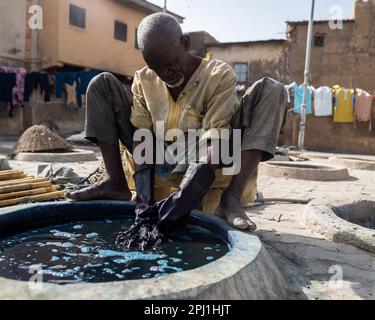 Ein Mann arbeitet in einer lokalen Textilindustrie in Kano. Kofar Mata Färbegruben ist eine lokale Textilindustrie in Kano, gegründet 1498 und die älteste im Bundesstaat Kano. Es soll etwa 250 Farbgruben haben, die zum Färben von Baumwollmaterialien und zur Herstellung verschiedener Designs auf Kleidung verwendet werden. Nigeria. Stockfoto