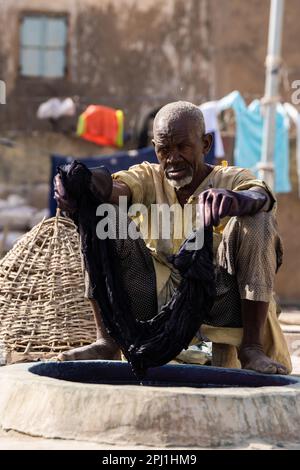 Ein Mann arbeitet in einer lokalen Textilindustrie in Kano. Kofar Mata Färbegruben ist eine lokale Textilindustrie in Kano, gegründet 1498 und die älteste im Bundesstaat Kano. Es soll etwa 250 Farbgruben haben, die zum Färben von Baumwollmaterialien und zur Herstellung verschiedener Designs auf Kleidung verwendet werden. Nigeria. Stockfoto